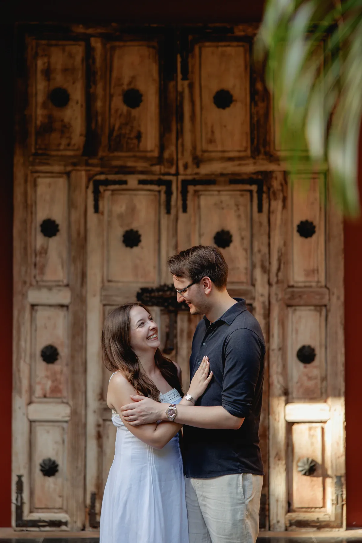 Ally and Marius embracing in front of a carved wooden door